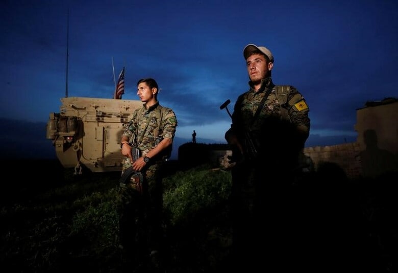 ５月９日、トランプ米大統領は、シリアで過激派組織「イスラム国」（ＩＳ）と戦うクルド人武装組織「人民防衛隊」（ＹＰＧ）に武器を供給することを承認した。写真は米国の軍用車のそばに立つＹＰＧ兵士。トルコのダルバシヤで４月撮影（２０１７年　ロイター／Rodi Said）