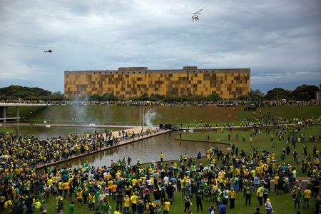　ブラジルのボルソナロ前大統領の支持者らが８日に連邦議会や大統領府、最高裁判所を襲撃した事件を受け、最高裁は同日夜、首都ブラジリアの知事を治安対応の不備を理由に９０日間職務停止とした。写真はブラジル議会周辺に集まるボルソナロ氏の支持者ら（２０２３年　ロイター／Antonio Cascio）