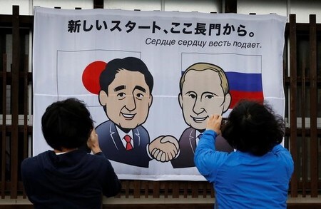 　１２月１４日、日露首脳会談を翌日に控えた山口県長門市では、安倍晋三首相とロシアのプーチン大統領が握手するイラストの描かれた横断幕が掲げられ、人々が写真を撮影していた（２０１６年　ロイター/Toru Hanai）