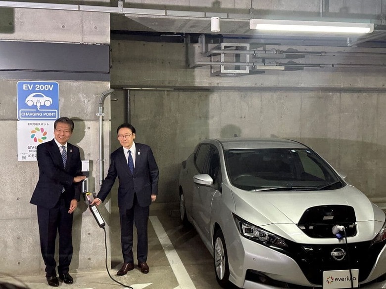 市川市役所第一庁舎の地下駐車場に設置された「everiwa Charger Share」登録のEV充電器を披露する大瀧社長と田中市長