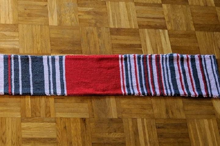 グレー、ピンク、赤で色分けされた手編みのマフラー　@sara_weber-Twitterより