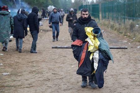 ベラルーシ当局はポーランドとの国境沿いで欧州連合（ＥＵ）入りを目指し野営していた移民を退去させた。写真は１８日、ベラルーシ・グロドノ地域のポーランド国境近くに集まる移民（２０２１年　ロイター／Kacper Pempel）